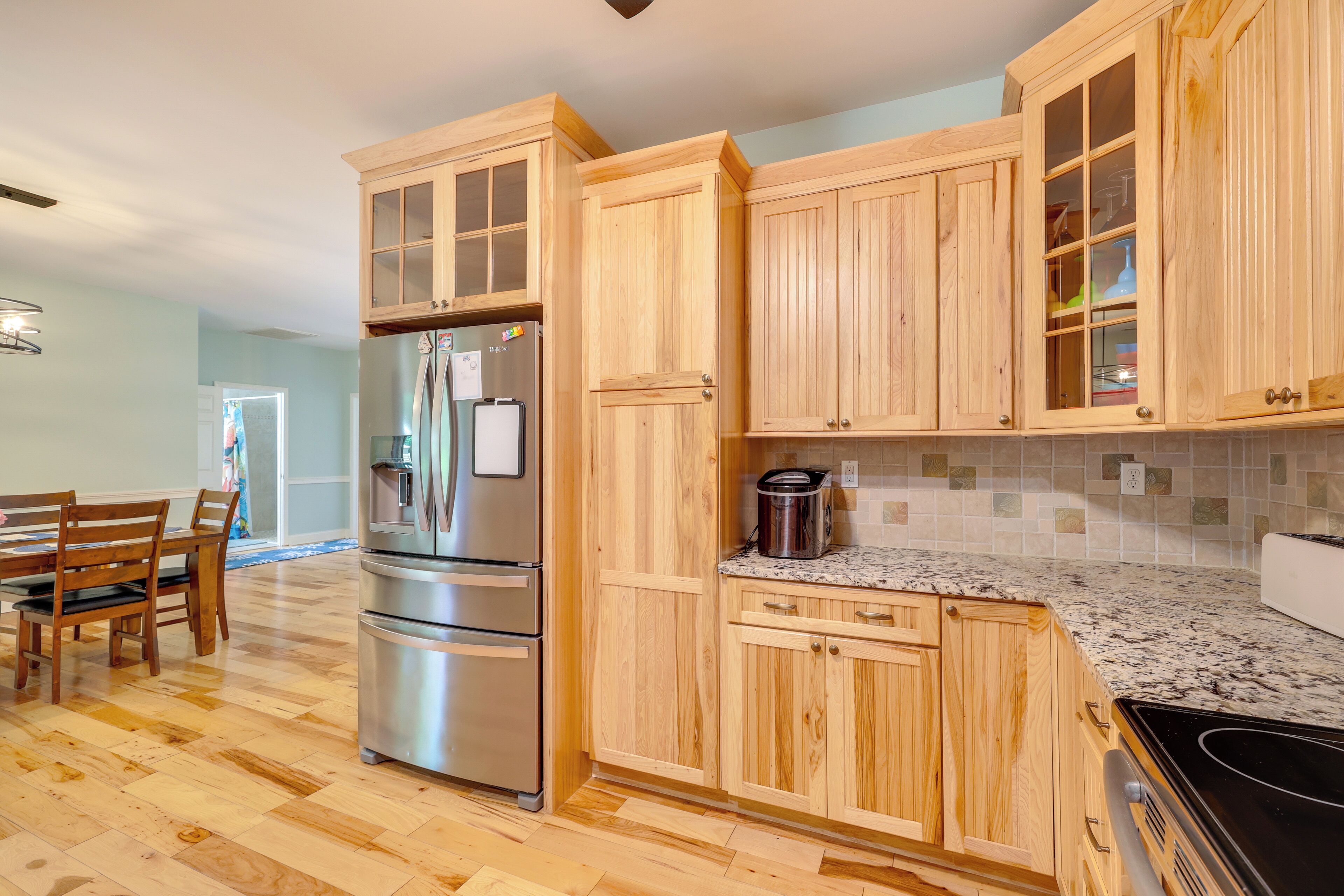 A kitchen with wooden cabinets, a stainless steel refrigerator, a granite countertop, and a black stove.