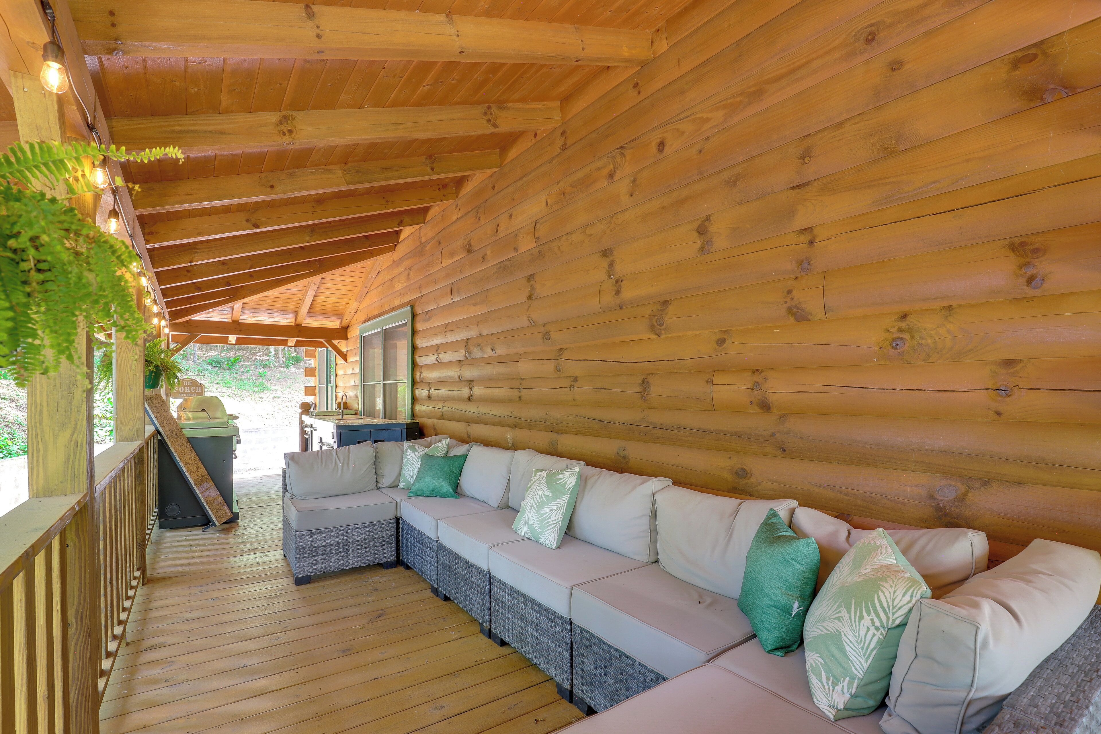 Una terrazza in legno con un divano integrato e un piccolo tavolo, circondata da pareti di legno e un soffitto a travi a vista.