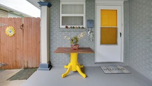 A front porch with a wooden table, a potted plant, a mailbox, and a door with a yellow panel. - 1 Mi to Airport! New Orleans Area Home (Kenner)
