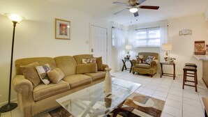 A living room with a sofa, armchair, coffee table, and ceiling fan. - 1 Mi to Airport! New Orleans Area Home (Kenner)