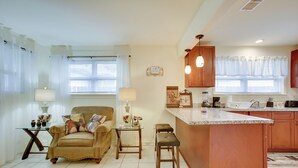 A modern kitchen with a central island, a dining area with a sofa and table, and a living room with a couch and a lamp. - 1 Mi to Airport! New Orleans Area Home (Kenner)