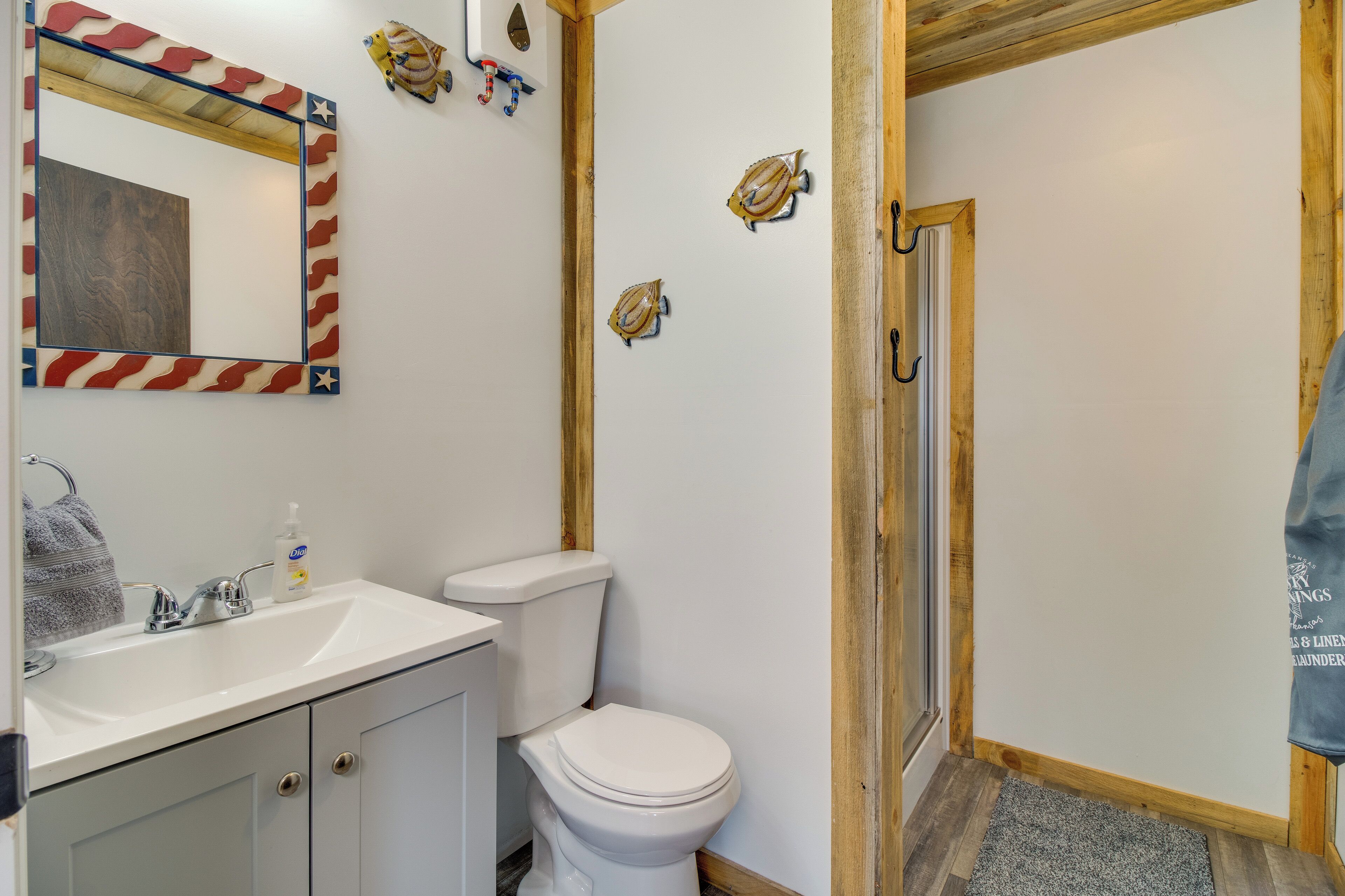Un bagno con lavandino, servizi igienici e specchio bianchi. Decorazioni a forma di pesce sulle pareti e un porta asciugamani con un asciugamano.