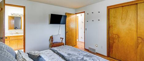 A bedroom with a bed, a chair, a television, and a wardrobe.
