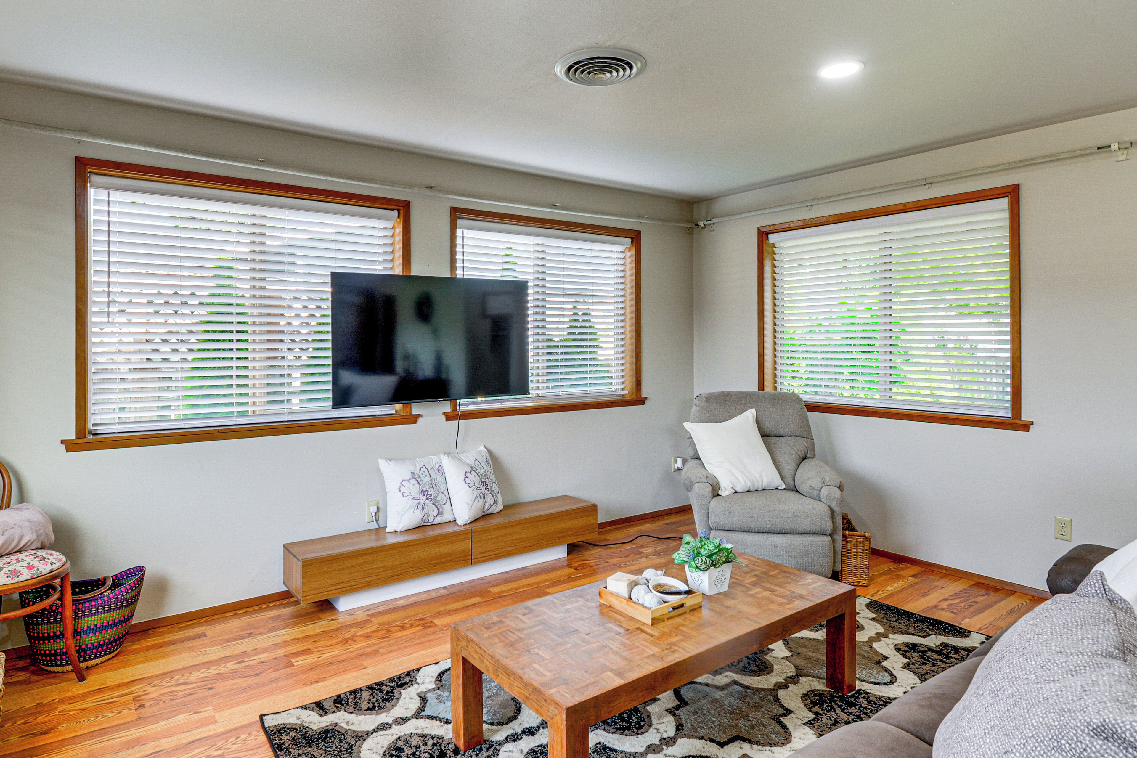A living room with a TV, a sofa, a chair, a coffee table, and a bench.