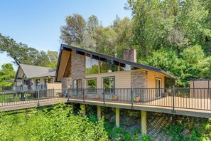 A modern house with a deck, stone walls, and a large window. - Walk to Dtwn Sonora! Rustic Creekfront Cabin (Sonora)