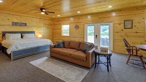 Interior de una cabaña de madera con cama, sofá y comedor.