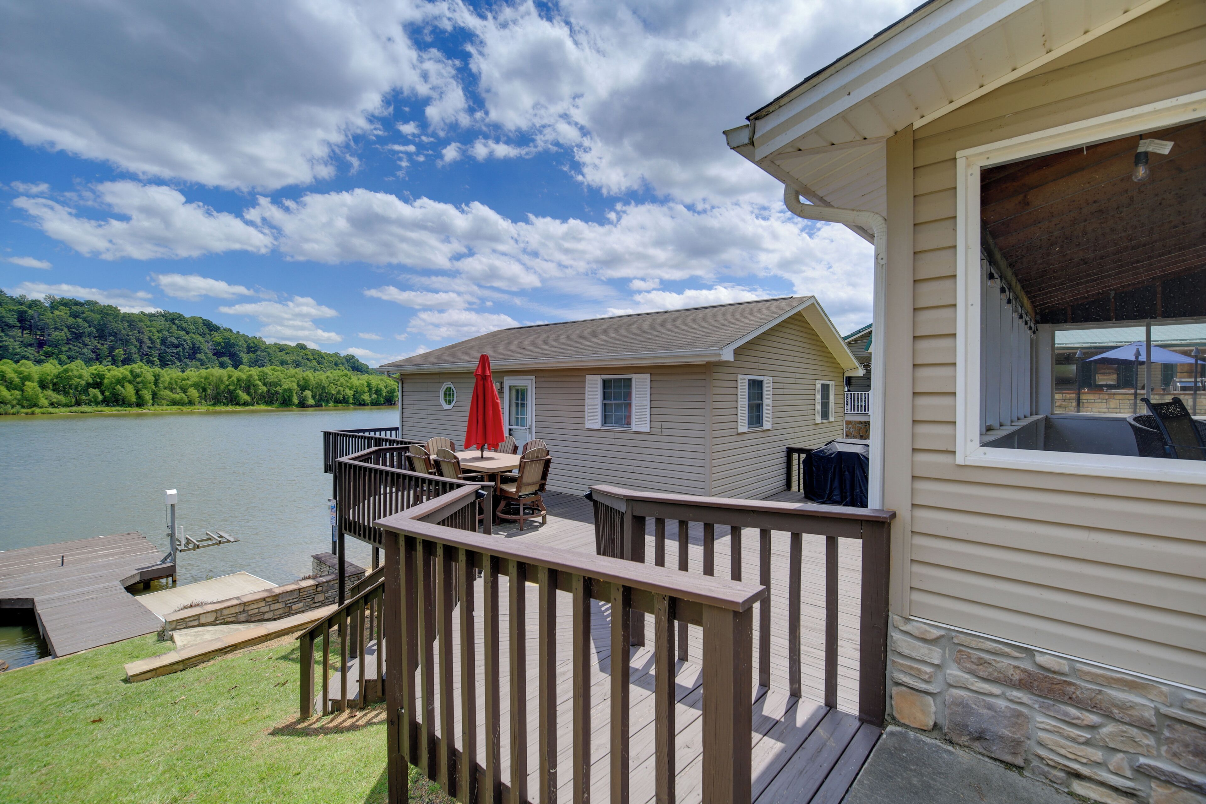 A deck with outdoor furniture, a stone wall, and a view of a lake.