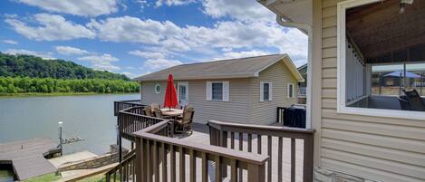 A deck with outdoor furniture, a stone wall, and a view of a lake.