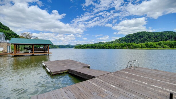 A wooden dock extending into a calm lake, surrounded by lush greenery and a clear sky. - Fire Pit & Floating Dock! Claytor Lake Hideout (Draper)