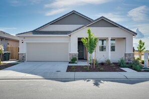 A single-story house with a garage, a small front yard with plants, and a clear sky. - Modesto Area Family Getaway w/ Patio & Backyard! (Modesto)
