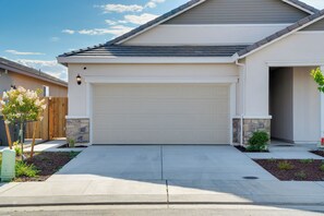 Ein Wohnhaus mit Garage, einer Akzentwand aus Stein und einem kleinen Garten mit Baum.