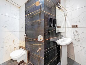 A modern bathroom with a toilet, bidet, and sink, featuring marble and black tiles. - Deluxe Indiranagar Leela Park Domlur (Bengaluru)