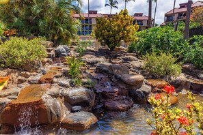 A naturalistic water feature with cascading water over rocks, surrounded by lush tropical vegetation. - White Sandy Beaches Just Steps Away!!  Paradise!!! (Kihei)