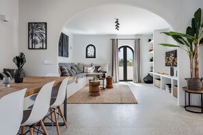 A modern living room with a sofa, coffee table, and dining area. - Authentic hacienda near the Mediterranean Sea (VC)