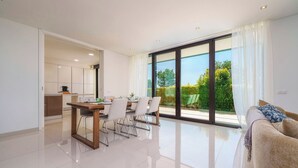 A modern living room with a dining area, large windows, and a view of greenery. - Bright Artistic 4-Bedroom Home in Faro | Newly Refurbished | 3 Bathrooms (Faro)