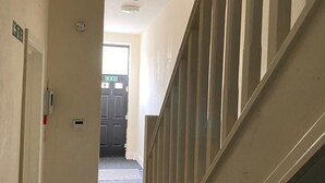 A hallway with a staircase, a door, and a light fixture on the ceiling. - House 2 Bedrooms Sleeps 4 With Parking (Bolton)