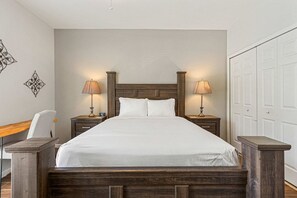 Ein Hotelzimmer mit einem großen Bett, zwei Nachttischen mit Lampen, einem hölzernen Kopfteil und einem Kleiderschrank.
