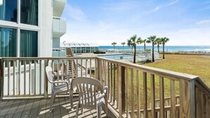 Un balcone con vista sull'oceano, una piscina e palme.