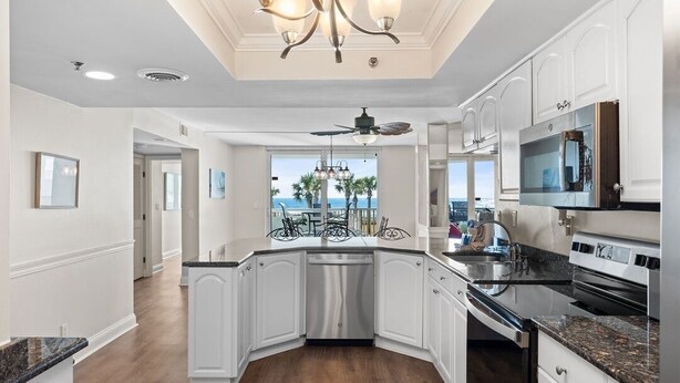 Una cucina moderna con mobili bianchi, lavastoviglie integrata, piano cottura in acciaio inossidabile e un'ampia finestra con vista panoramica.
