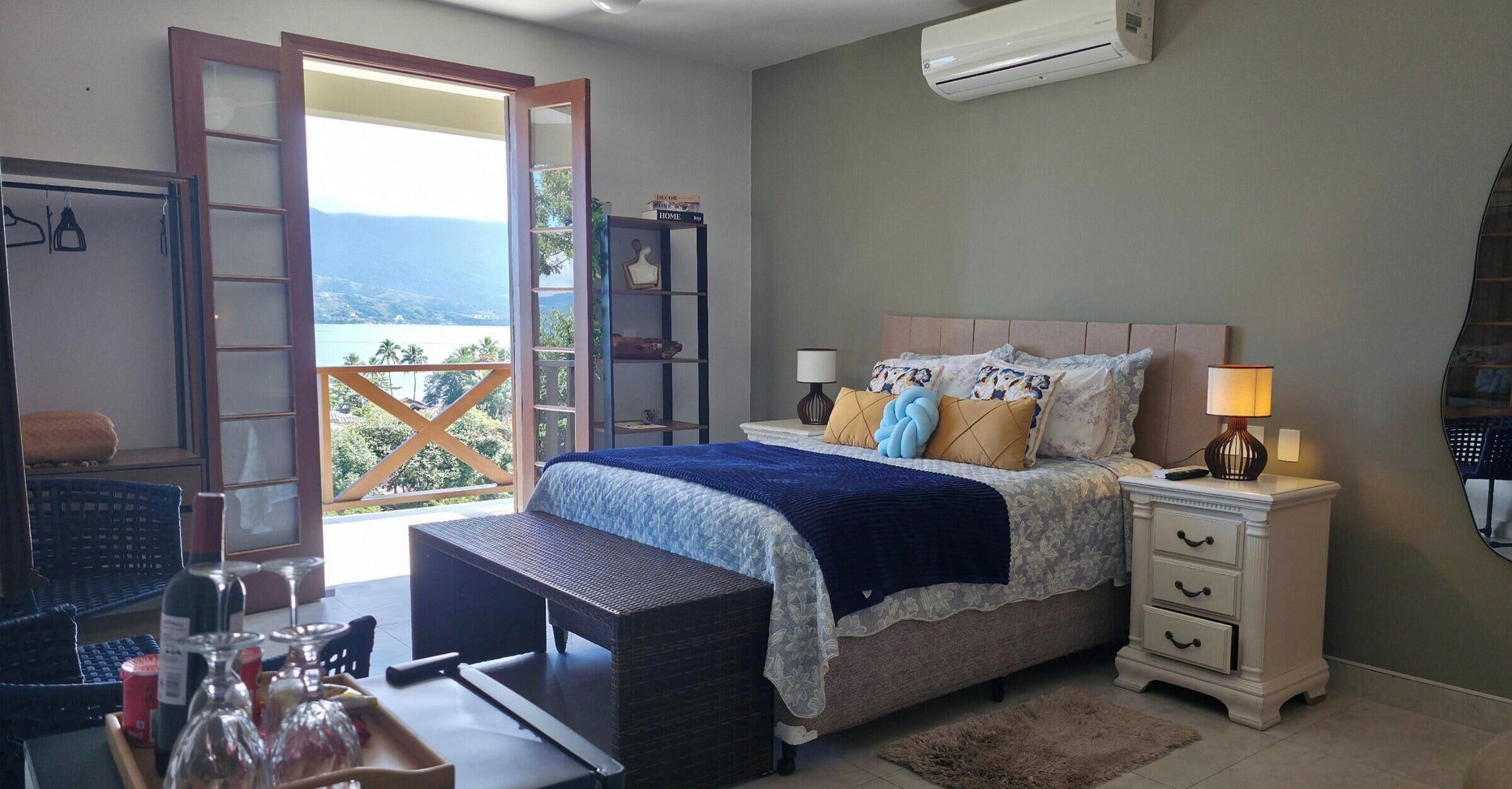 A bedroom with a bed, bedside tables, a nightstand, a window with a view, and a balcony.