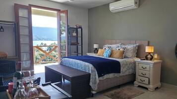 A bedroom with a bed, bedside tables, a nightstand, a window with a view, and a balcony.