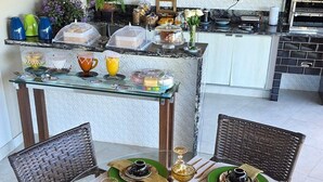 A dining area with a glass-top table set for six, surrounded by wicker chairs. - A Casa Bella Guest House - Ilhabela (Ilhabela)