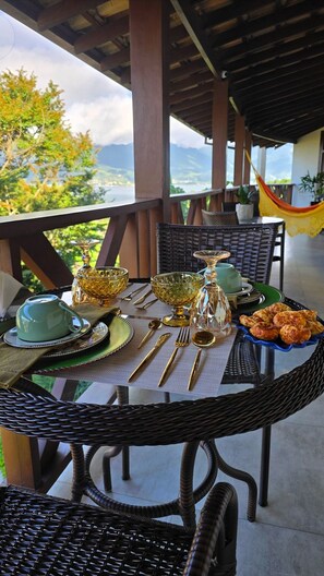 Una mesa de comedor dispuesta con cristalería, platos y cubiertos, con vistas a un paisaje pintoresco.