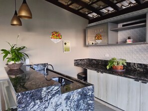 Una cocina moderna con una isla de mármol, iluminación colgante y detalles decorativos en la pared.