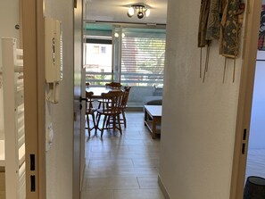 A hallway leading to a dining area with a table and chairs, a ceiling light fixture, and a window with blinds. - Renovated apartment with parking - 4 guests (Hyères)