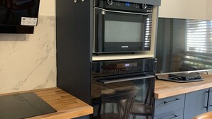 Eine Küche mit eingebauter Mikrowelle, Backofen und einer Holz Arbeitsplatte.