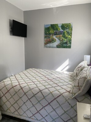 A bedroom with a bed, a painting on the wall, and a TV mounted on the wall. - Escape to a quaint and peaceful slice of Heaven on Earth!
In Youngstown, NY (Youngstown)