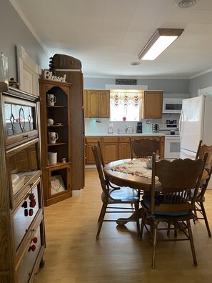 Una cocina con gabinetes de madera, una mesa de comedor con sillas y un refrigerador.