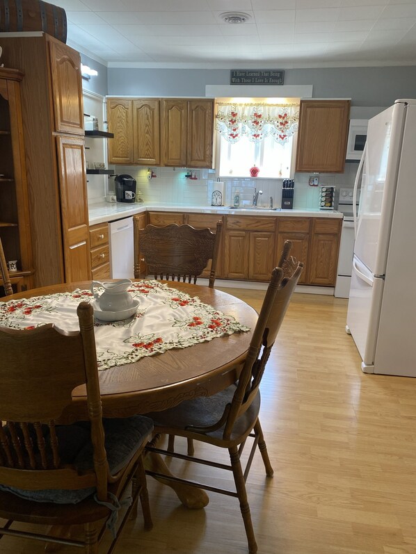 A kitchen with wooden cabinets, a dining table with chairs, and a refrigerator.