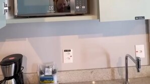 A kitchen with a microwave on a shelf, a coffee maker, and a sink. - Fully Equipped Studio Apartment (Joinville)