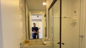 A modern bathroom with a glass shower enclosure, a sink with a mirror, and a toilet. - Fully Equipped Studio Apartment (Joinville)