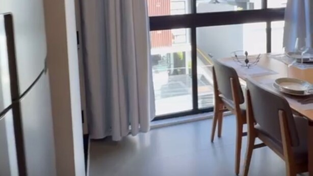 A modern room with a dining table, chairs, a window with curtains, and an air conditioning unit. - Fully Equipped Studio Apartment (Joinville)