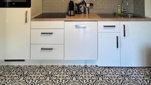 A modern kitchen with white cabinets, a built-in oven, a coffee maker, and a sink. - Auszeit in Willingen - Erdgeschoss Wohnung (Willingen)