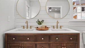 Une salle de bain avec deux lavabos, un meuble-lavabo en bois et deux grands miroirs.
