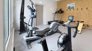 A gym with cardio machines, a rowing machine, and a wall-mounted TV. - Mobil-home in the heart of Jullouville - 6 guests (Jullouville)