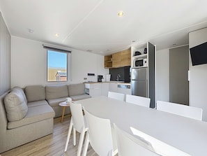 Eine moderne Küche mit weißen Schränken, einem Edelstahl-Kühlschrank und einem Essbereich mit weißem Tisch und Stühlen.