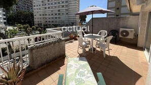 Une terrasse sur le toit, avec une table et des chaises, un pot de fleurs et une vue sur les bâtiments environnants.