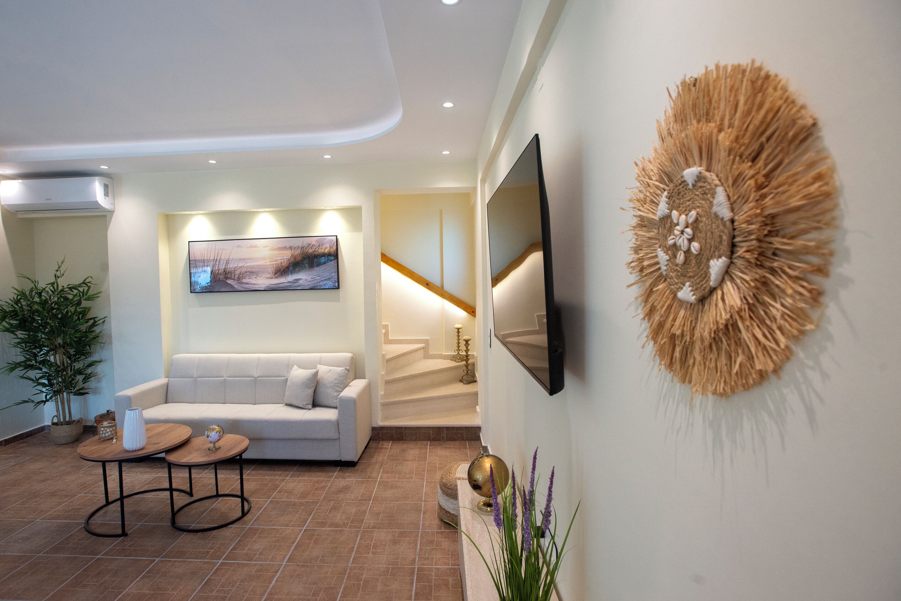 Una sala de estar moderna con sofá, mesa de centro, televisor y arte decorativo en la pared.