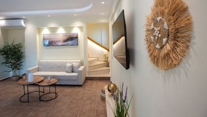 A modern living room with a sofa, coffee table, TV, and decorative wall art. - Villa Praxithea (Lakka)