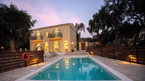 A two-story building with a swimming pool, stone flooring, and a wooden fence. - Villa Praxithea (Lakka)