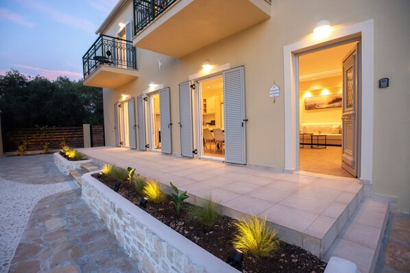 A building with a balcony, multiple doors, and a well-lit interior. - Villa Praxithea (Lakka)
