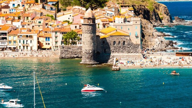 A coastal town with historic buildings, a prominent tower, and a beach with boats. - Mobile home with AC - 6 guests (Canet-en-Roussillon)