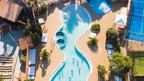 An aerial view of a swimming pool with a unique shape, surrounded by lounge chairs and palm trees. - Mobile home with AC - 6 guests (Canet-en-Roussillon)