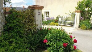 A residential building with a gated entrance, a number '95' sign, and a variety of flowering plants. - Historic cottage, pets OK - 4 guests (Vennecy)