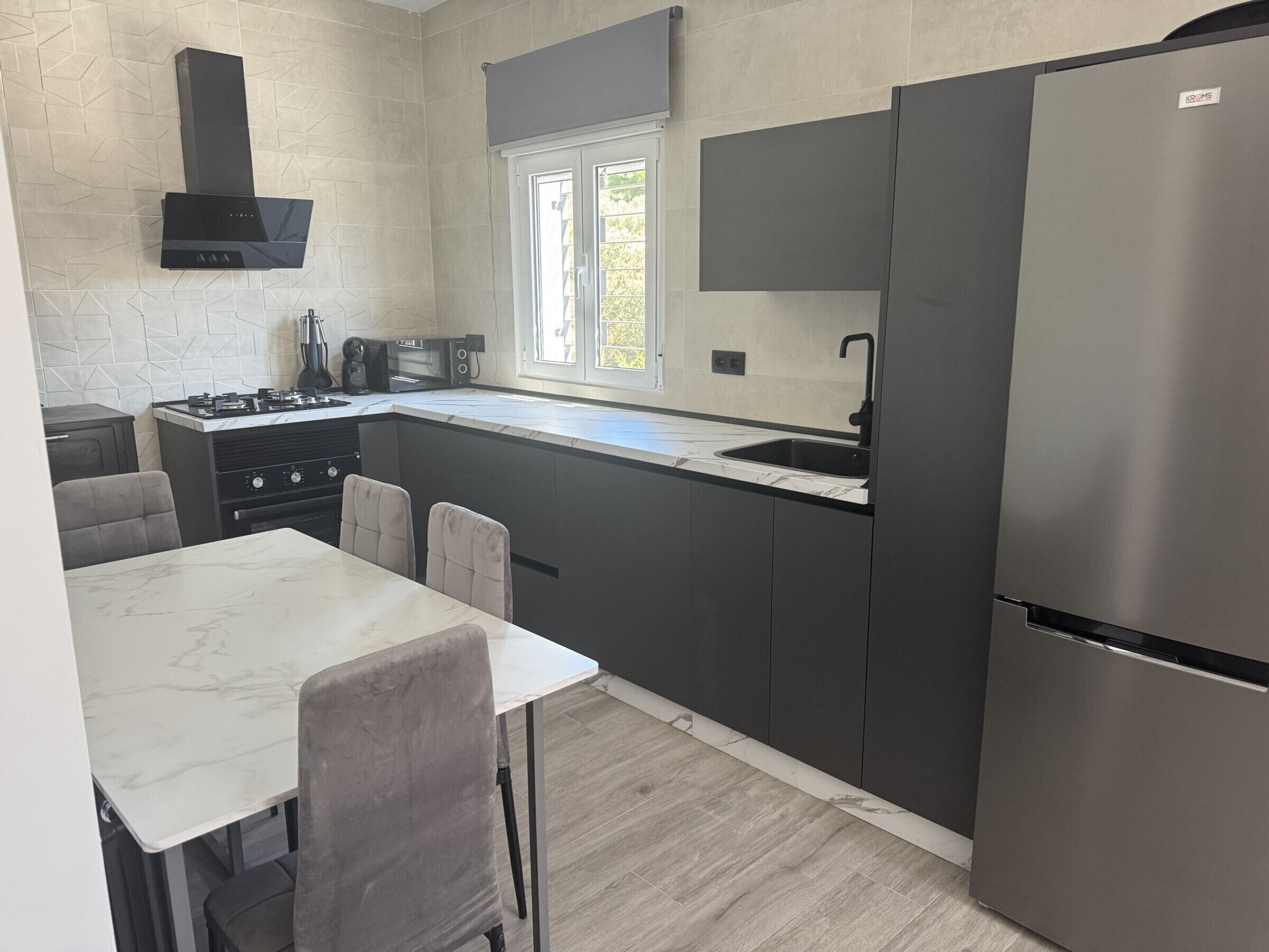 A modern kitchen with a built-in stove, a microwave, and a stainless steel refrigerator.