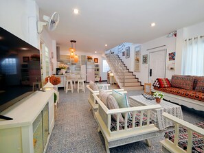 A modern living room with a sofa, a dining area, and a staircase leading to an upper floor. - Old Town Hideaway/Walk Everwhere/Tha Phae Gate (Chang Wat Chiang Mai)